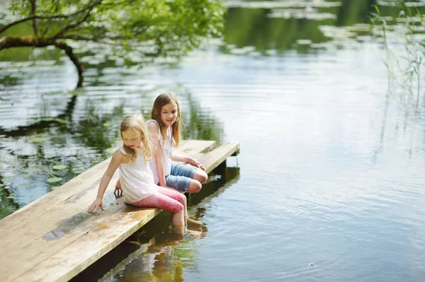 Duas Meninas Bonitinhas Sentadas Uma Plataforma Madeira Junto Rio Lago — Fotografia de Stock