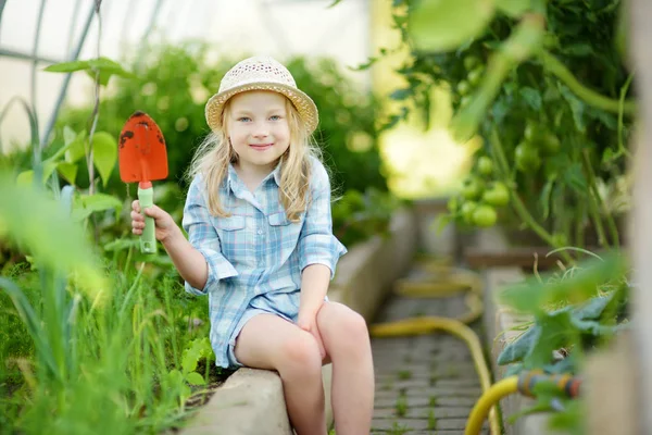 可爱的小女孩戴着草帽 在阳光明媚的夏日 在温室里玩着她的玩具花园工具 小孩子的园艺活动 — 图库照片