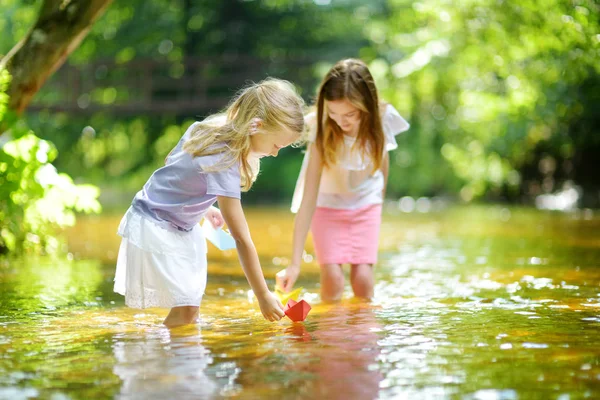 遊んで二つの妹は暖かく 日当たりの良い夏の日に川でのボートを紙します 水で楽しい様子 小さな子供のための夏の活動 — ストック写真