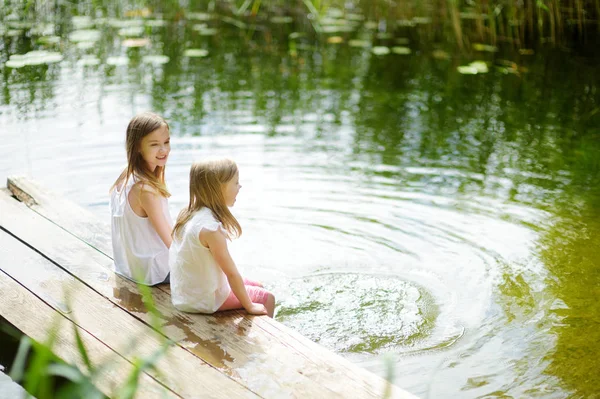 Duas Meninas Bonitinhas Sentadas Uma Plataforma Madeira Junto Rio Lago — Fotografia de Stock