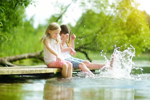 川や湖の暖かい夏の日に水に足を浸漬して木製の台の上に座って 人のかわいい少女 夏の家族の活動 — ストック写真