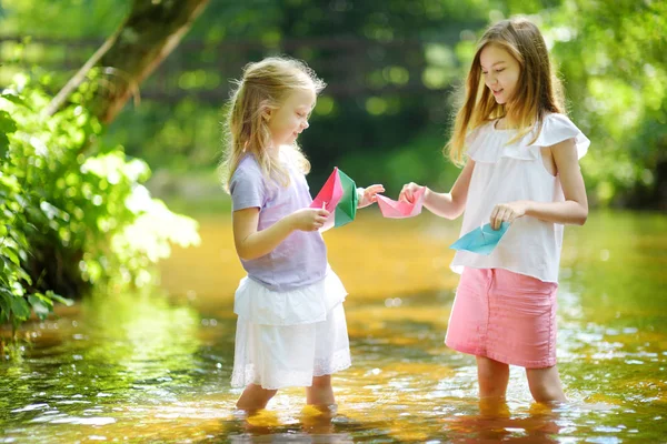 遊んで二つの妹は暖かく 日当たりの良い夏の日に川でのボートを紙します 水で楽しい様子 小さな子供のための夏の活動 — ストック写真