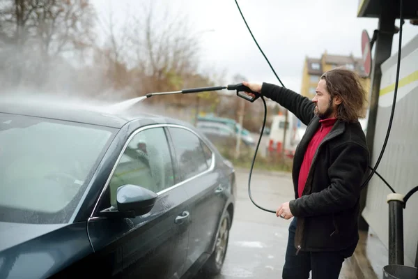 年轻人用高压垫圈洗车 在加油站用泡沫和加压水手动清洗汽车 — 图库照片