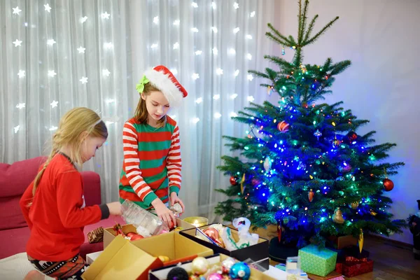 两个可爱的姐妹在家里装饰一棵五颜六色的玻璃华而不实圣诞树 家庭休闲在美妙的圣诞节时间 修剪一棵喜庆的树 — 图库照片