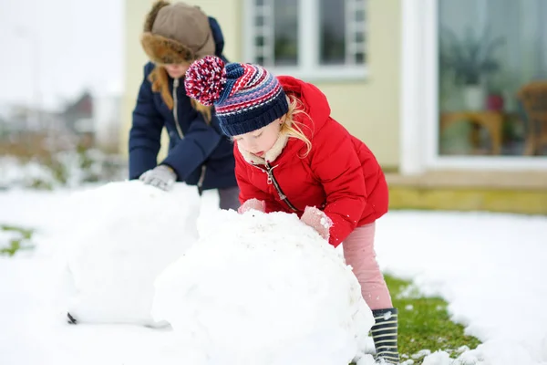可爱的小女孩在后院堆雪人 可爱的孩子们在雪地里玩耍 儿童冬季活动 — 图库照片