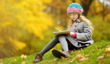 Sevimli küçük kız dışında güzel sonbahar gününde çizimi. Sonbahar Parkta oynayan mutlu çocuk. Çocuk ile renkli kalemler çizim. Çocuklar için sonbahar faaliyetleri.