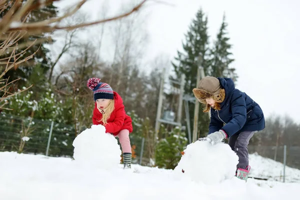 Urocze Dziewczynki Budowanie Bałwana Podwórku Słodkie Dzieci Bawiące Się Śniegu — Zdjęcie stockowe