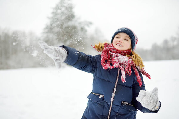 Очаровательная маленькая девочка развлекается в красивом зимнем парке. Милый ребенок, играющий в снегу. Зимние развлечения для детей
.
