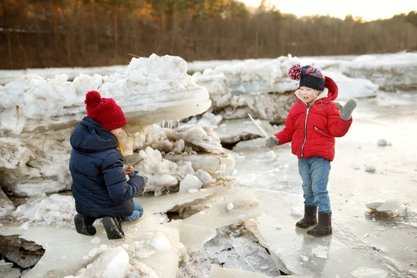 两个快乐的姐妹在冰歇期间在冰冻的河边玩冰块 孩子们在冬天玩得开心 儿童冬季活动 — 图库照片