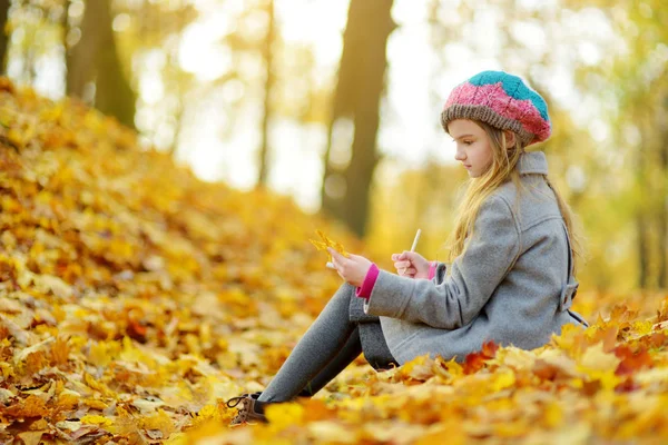 可爱的小女孩在美丽的秋日外素描 快乐的孩子在秋季公园玩 用彩色铅笔画画的孩子 儿童秋季活动 — 图库照片