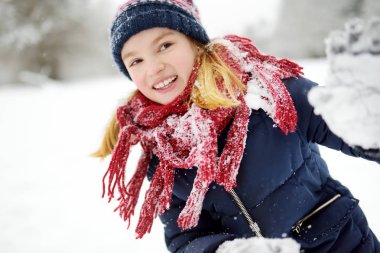 Sevimli küçük kız güzel kış Park eğleniyor. Bir karda oynayan sevimli çocuk. Çocuk için kış aktiviteleri.