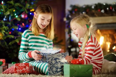 Mutlu küçük kız Noel arifesinde bir şömine karanlık bir odada rahat yaşam hediye kutuları açmalarına Noel pijama giyiyor. Xmas evde kutlama.