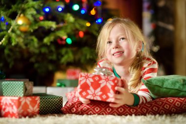 Noel arifesinde bir rahat karanlık oturma odasında şömine tarafından oynarken Noel pijama giymiş mutlu küçük kız. Xmas evde kutlama.