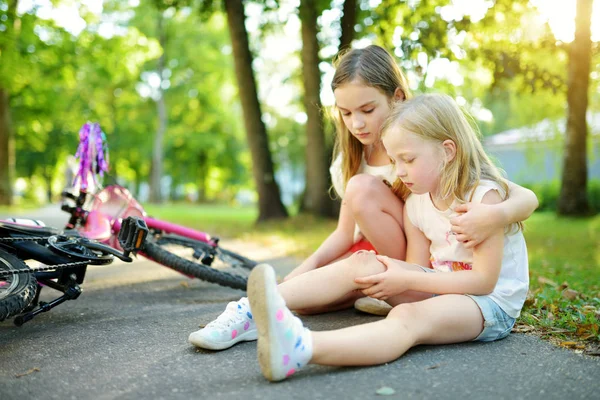 彼女は夏の公園で彼女の自転車から落ちた後 妹を慰める愛らしい少女 自転車に乗りながら怪我の子 子供と家族レジャー — ストック写真
