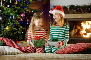Mutlu küçük kız Noel arifesinde bir şömine karanlık bir odada rahat yaşam hediye kutuları açmalarına Noel pijama giyiyor. Xmas evde kutlama.