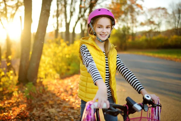 在阳光明媚的秋日 可爱的小女孩在城市公园骑自行车 积极的家庭休闲与孩子 骑自行车时戴安全半身像的儿童 — 图库照片