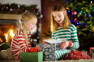 Mutlu küçük kız Noel arifesinde bir şömine karanlık bir odada rahat yaşam hediye kutuları açmalarına Noel pijama giyiyor. Xmas evde kutlama.