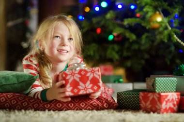 Noel arifesinde bir rahat karanlık oturma odasında şömine tarafından oynarken Noel pijama giymiş mutlu küçük kız. Xmas evde kutlama.