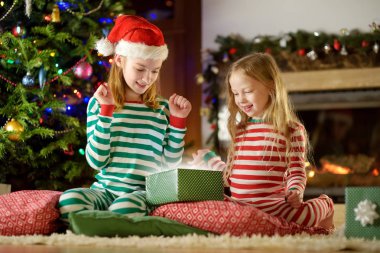 Mutlu küçük kız Noel arifesinde bir şömine karanlık bir odada rahat yaşam hediye kutuları açmalarına Noel pijama giyiyor. Xmas evde kutlama.