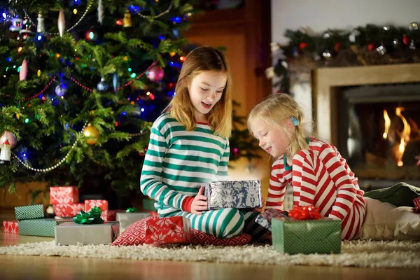 Mutlu küçük kız Noel arifesinde bir şömine karanlık bir odada rahat yaşam hediye kutuları açmalarına Noel pijama giyiyor. Xmas evde kutlama.