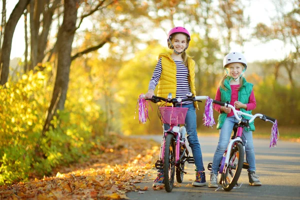 かわいい妹晴れた秋の日に都市公園でバイクに乗る 子供とアクティブなファミリー向けのレジャーです 自転車に乗りながら安全ヘメットを着た子供たち — ストック写真