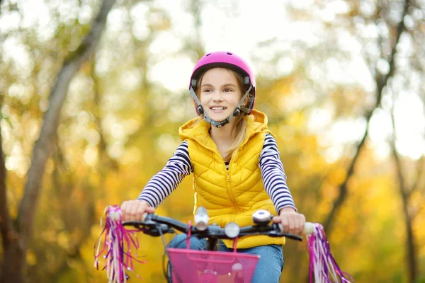 在阳光明媚的秋日 可爱的小女孩在城市公园骑自行车 积极的家庭休闲与孩子 骑自行车时戴安全半身像的儿童 — 图库照片