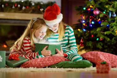 Mutlu küçük kız Noel arifesinde bir şömine karanlık bir odada rahat yaşam hediye kutuları açmalarına Noel pijama giyiyor. Xmas evde kutlama.