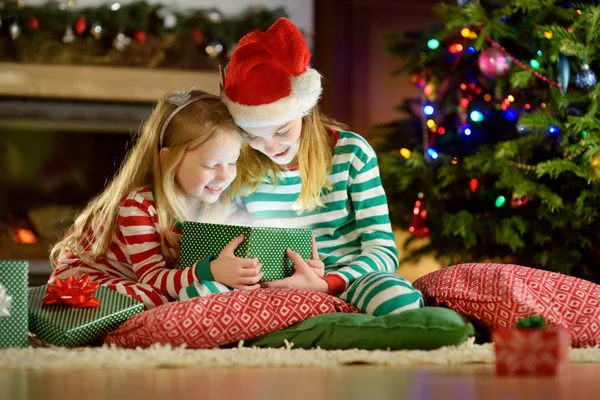 Mutlu küçük kız Noel arifesinde bir şömine karanlık bir odada rahat yaşam hediye kutuları açmalarına Noel pijama giyiyor. Xmas evde kutlama.