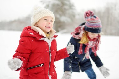 Güzel kış park içinde birlikte eğleniyor iki sevimli küçük kız. Güzel kız bir karda oynarken. Çocuklar için kış aktiviteleri.
