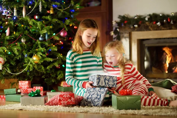 Щасливі Маленькі Сестри Різдвяній Піжамі Відкривають Подарункові Коробки Біля Каміна — стокове фото