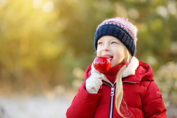 Αξιολάτρευτο Κοριτσάκι Που Τρώει Κόκκινο Μήλο Που Καλύπτονται Ζάχαρη Άχνη — Φωτογραφία Αρχείου