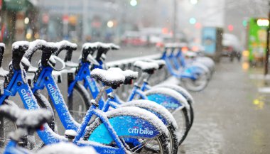 NEW YORK - MARCH 19, 2015: Row of City bike rental bicycles at docking station in New York City during snowfall clipart