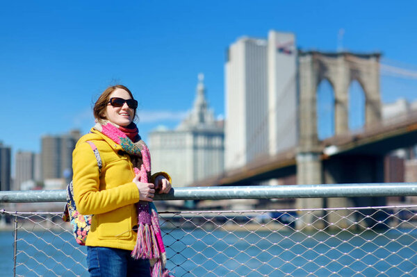 Happy young woman tourist sightseeing by Brooklyn Bridge, New York City