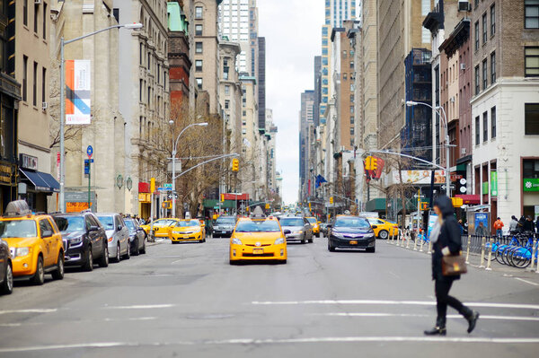 NEW YORK - MARCH 16, 2015: Yellow taxi cabs and people rushing on busy streets of downtown Manhattan