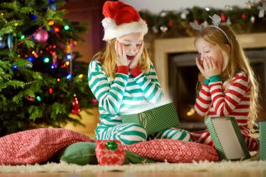 Şöminenin yanında hediye kutuları açma Noel pijama giymiş mutlu küçük kız 