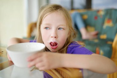 Sevimli küçük kız büyük beyaz bardağı taze organik süt içme