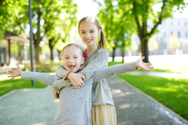 在公园温暖阳光明媚的夏日里 两个可爱的姐妹笑着拥抱着 — 图库照片