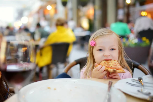 可爱有趣的小女孩吃比萨饼在户外餐厅在夏天晚上 — 图库照片