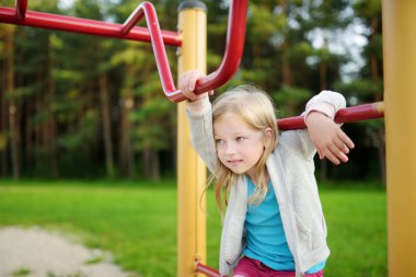 Sevimli küçük kız oyun bahçesinde açık havada yaz aylarında eğleniyor