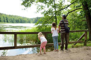 İki sevimli genç kız ormandaki göl güzel yaz gününde babalarıyla hiking