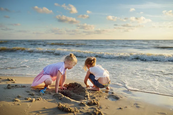 海で夏の日の暖かい日当たりの良い砂浜で楽しい時を過すかわいい若い姉妹 — ストック写真