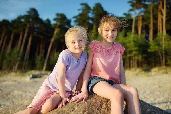 两个可爱的年轻姐妹在沙滩上享受温暖阳光明媚的夏日在海上 — 图库照片