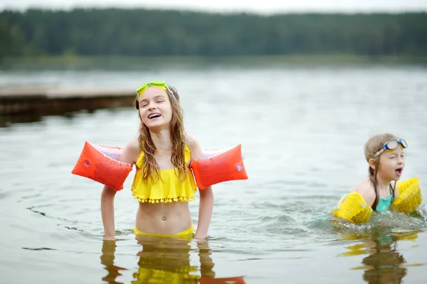 人の若い姉妹は暖かく 日当たりの良い夏の日の湖の砂浜ビーチで楽しんで — ストック写真