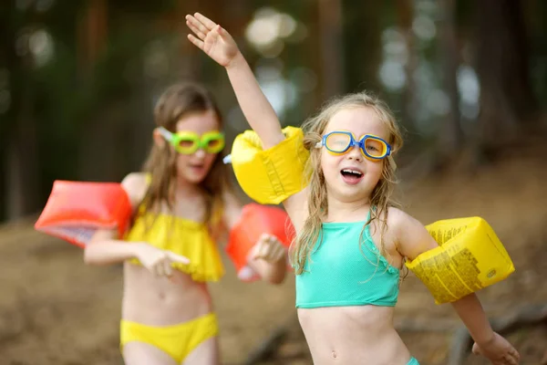 人の若い姉妹は暖かく 日当たりの良い夏の日の湖の砂浜ビーチで楽しんで — ストック写真