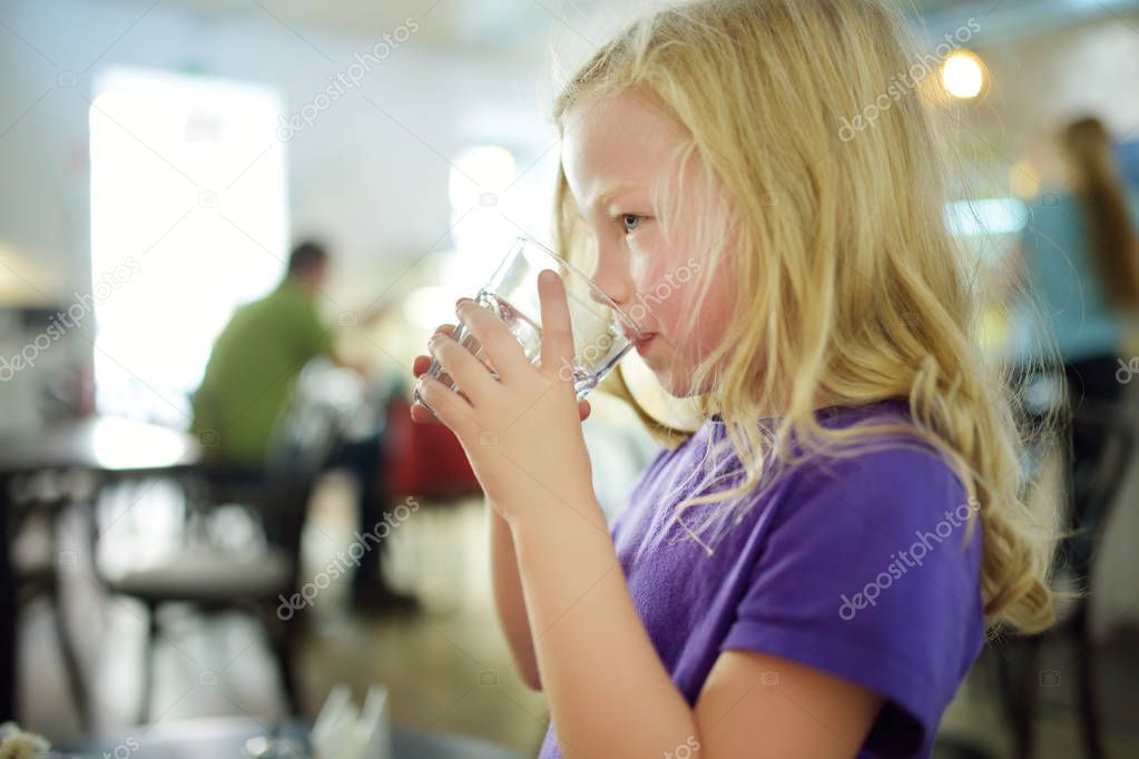 Cute little girl drinking water on hot summer day