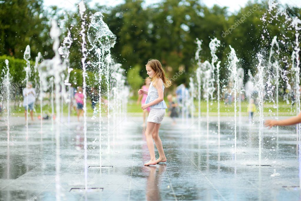Cute preteen girl playing in fountains on newly renovated Lukiskes Square in Vilnius, Lithuania