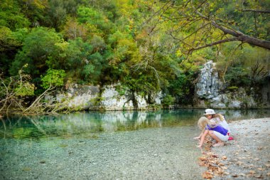 Zagoria, Yunanistan için aile tatil sırasında sıcak ve güneşli yaz gününde Voidomatis nehir kenarında eğleniyor iki sevimli genç kız kardeş