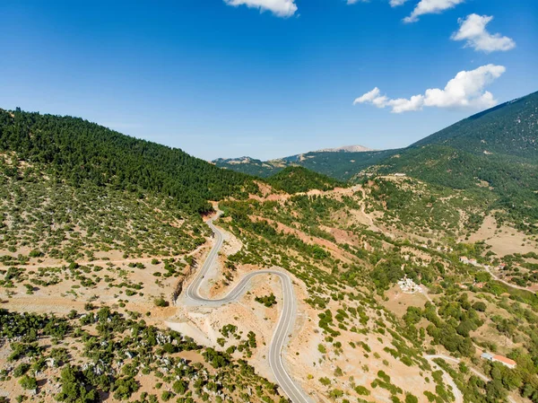 Вид с воздуха на змеиную дорогу между горами в Западной Греции. В греческом регионе Пелопоннес в гору резко взмывает дорога, полная фур и поворотов . — стоковое фото