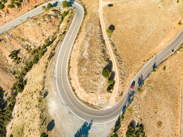 Aerial view of serpentine road snaking between mountains in West Greece. A road full of twists and turns winding sharply up the mountain in Peloponnese region, Greece. — Stock Photo, Image