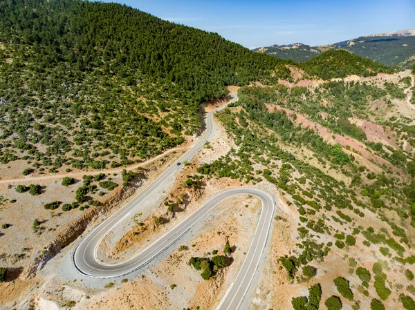 Aerial view of serpentine road snaking between mountains in West Greece. A road full of twists and turns winding sharply up the mountain in Peloponnese region, Greece. — Stock Photo, Image